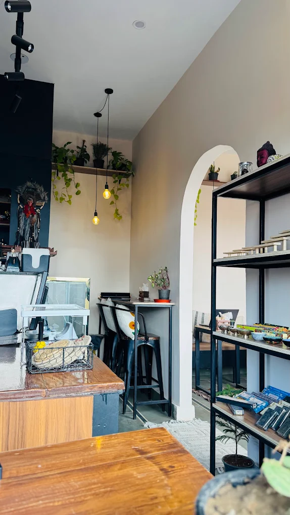 Archway into the café interior with shelving, counter, and pendant lighting at One Coffee Down