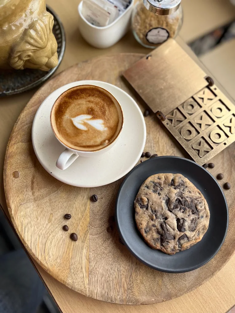 Cappuccino and pastries laid out on a wooden tray with coffee beans